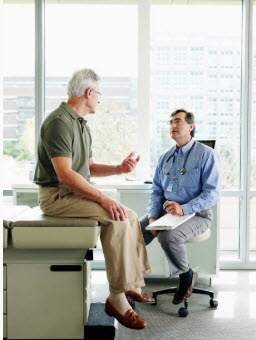 Senior man sitting on an examining table having a conversation with a male physician